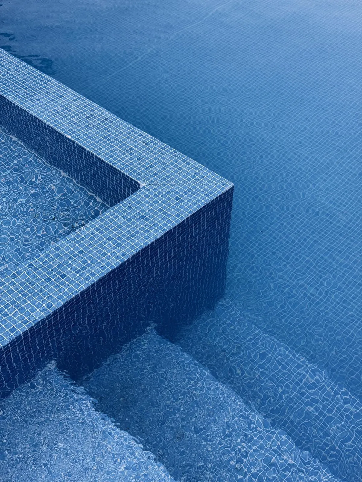Blue tiled pool steps under clear water