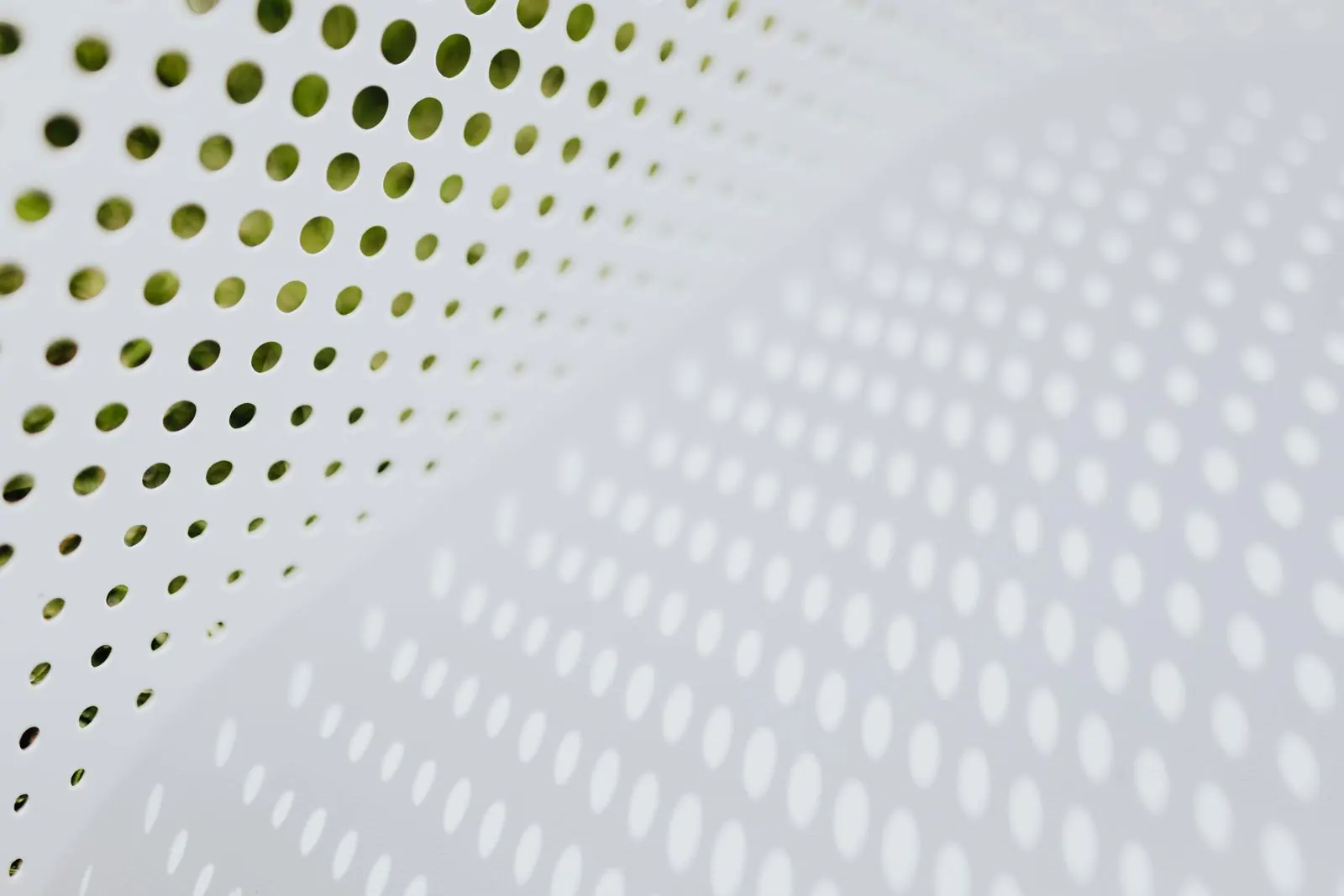 White perforated panel with green leaves behind it